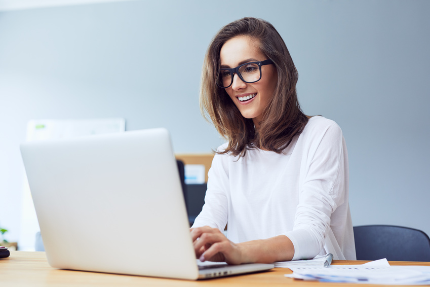Front view of attractive lady working on laptop and smiling in modern home office Front view of attractive lady working on laptop and smiling in modern home office